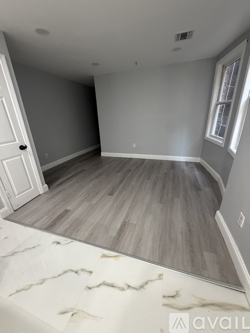 A room with wooden flooring and a marble patterned floor.
