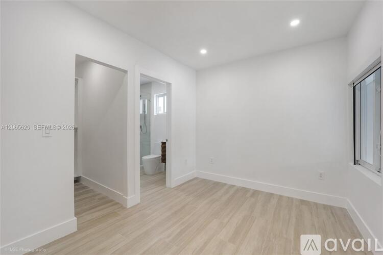 A spacious room with wooden flooring and white walls.