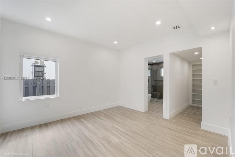 A spacious room with wooden flooring and a window overlooking a cityscape.