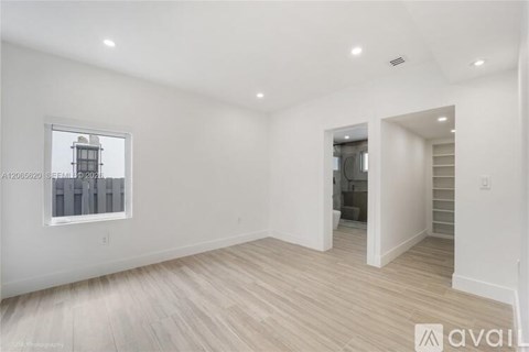 A spacious room with wooden flooring and a window overlooking a cityscape.