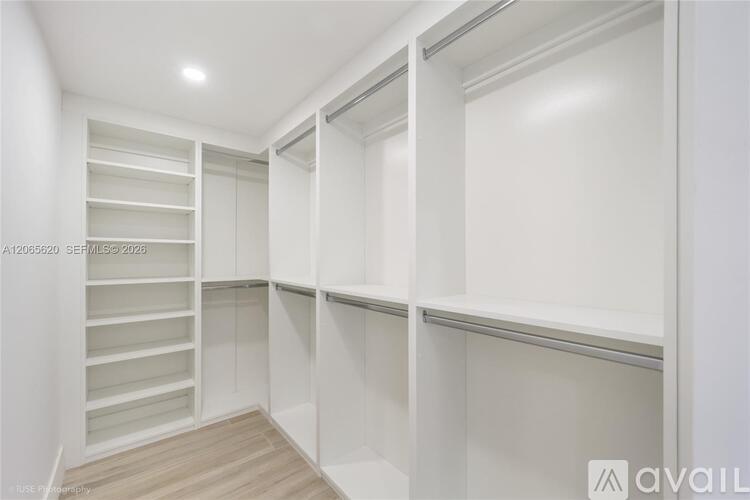 A white pantry with shelves and a wooden floor.