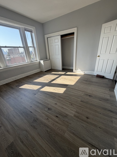 A room with wooden flooring and a large window.