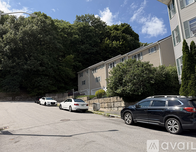 Cars parked on a street in front of apartment buildings.