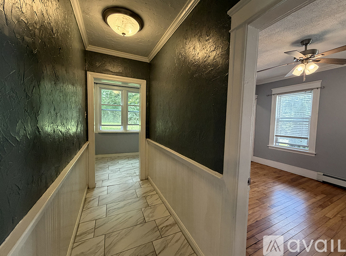 A hallway with a wooden floor and a ceiling fan.