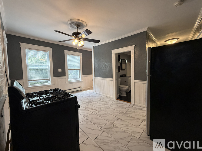 A kitchen with a black stove top oven and a fan on the ceiling.