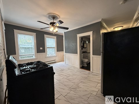 A kitchen with a black stove top oven and a fan on the ceiling.