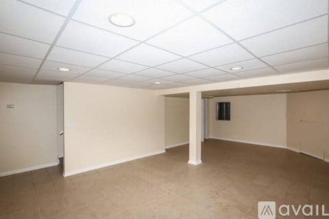 A spacious room with beige walls and floor, and a white ceiling with recessed lighting.