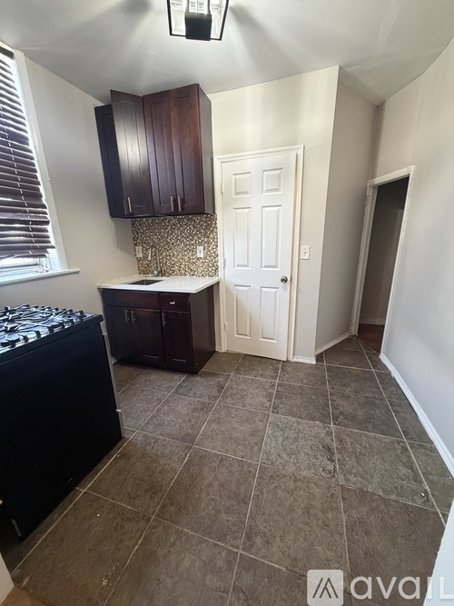 A kitchen with a black stove top oven and dark brown cabinets.