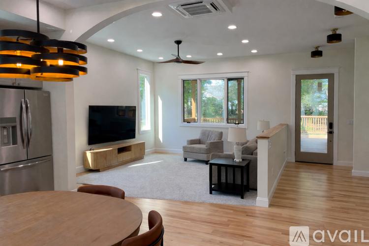 A modern kitchen with a wooden table and a television.
