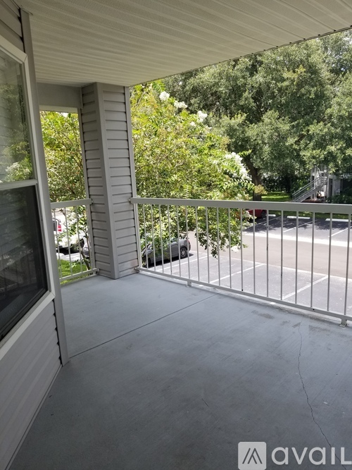 A balcony with a metal railing and a view of a street and trees.