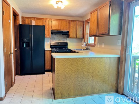 A kitchen with wooden cabinets and a black refrigerator.
