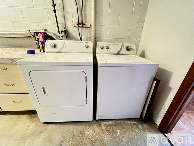 Two white washing machines in a laundry room.