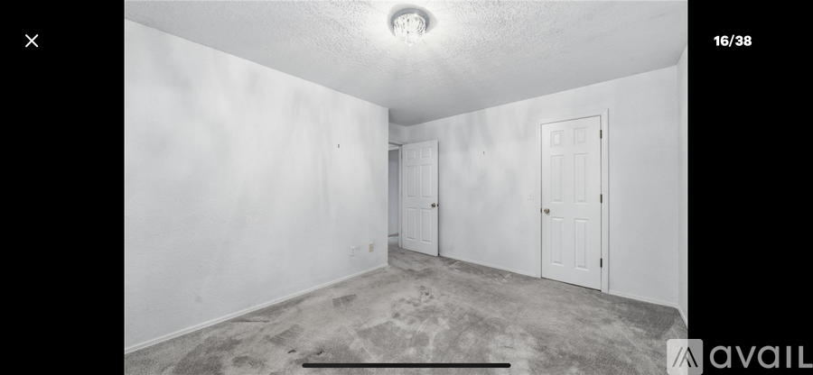 A room with white walls and a carpeted floor with a door on the right.