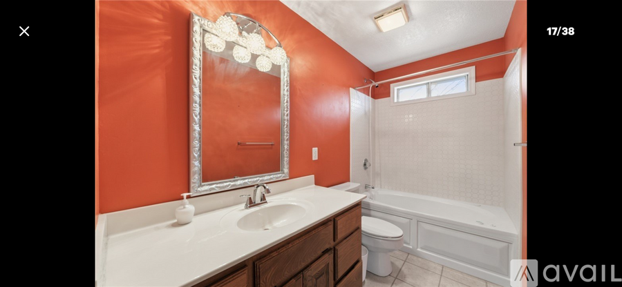 A bathroom with orange walls and a white sink.