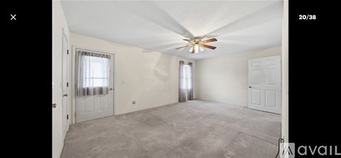 A spacious room with a ceiling fan and two windows.