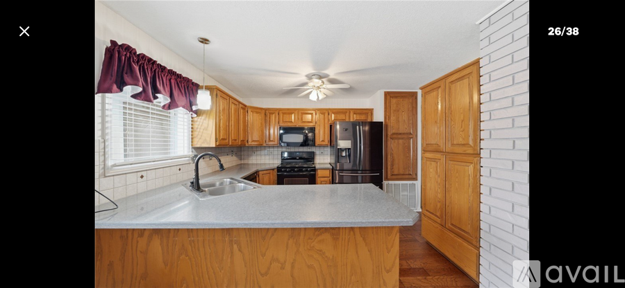 A kitchen with wooden cabinets and a white ceiling fan.