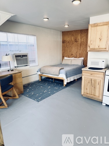 A bedroom with a bed, desk, chair, and a microwave.