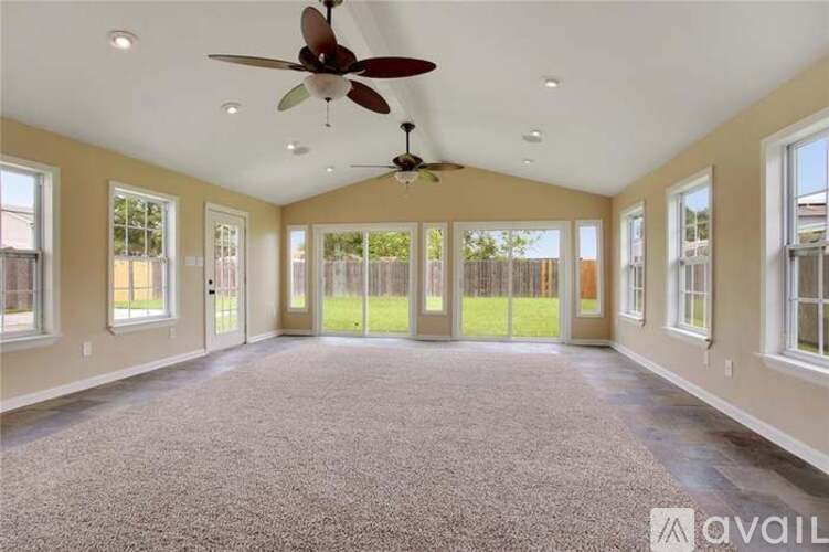 A spacious room with a ceiling fan and carpeted floor.