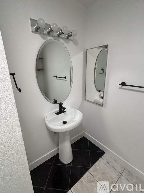 A white sink with a round mirror above it.