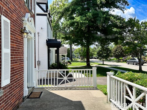 A white house with a black awning and a white fence.