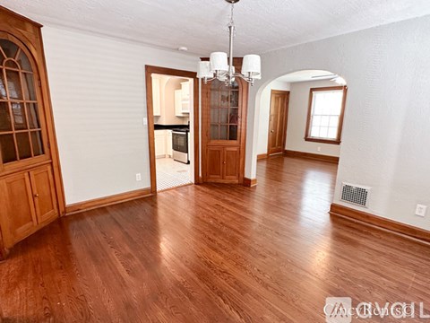 A living room with a chandelier and hardwood floors.