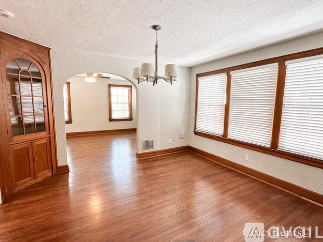 A spacious room with wooden floors and a chandelier.