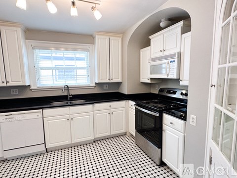 A kitchen with black and white tiles on the floor.