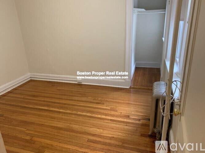 A room with wooden flooring and a wall-mounted air conditioning unit.