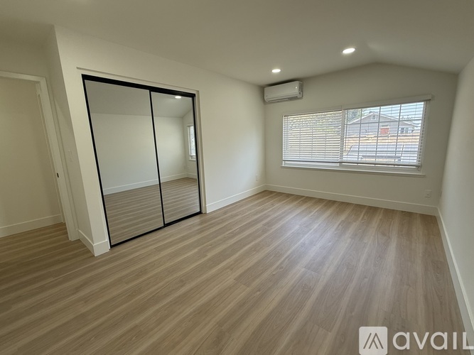 A room with wooden flooring and a sliding door leading to a balcony.