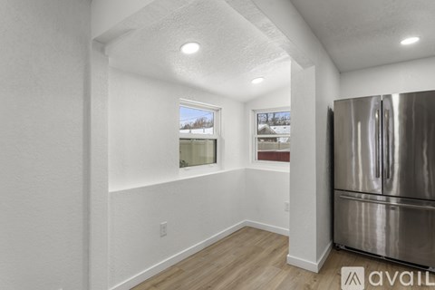 A kitchen with a stainless steel refrigerator and wooden flooring.