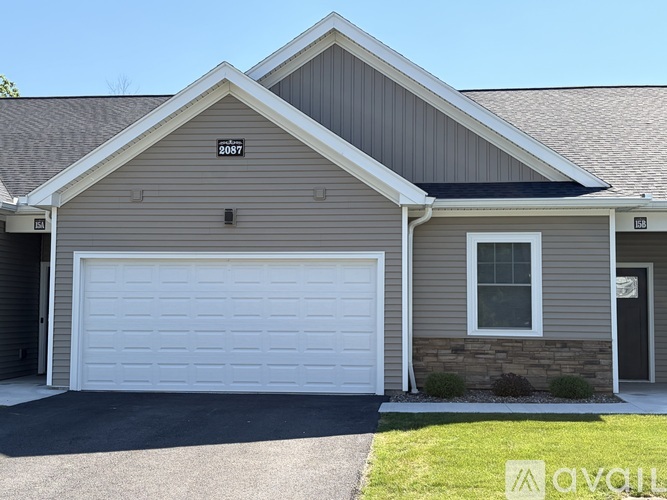 A two-car garage with a white door is attached to a house.