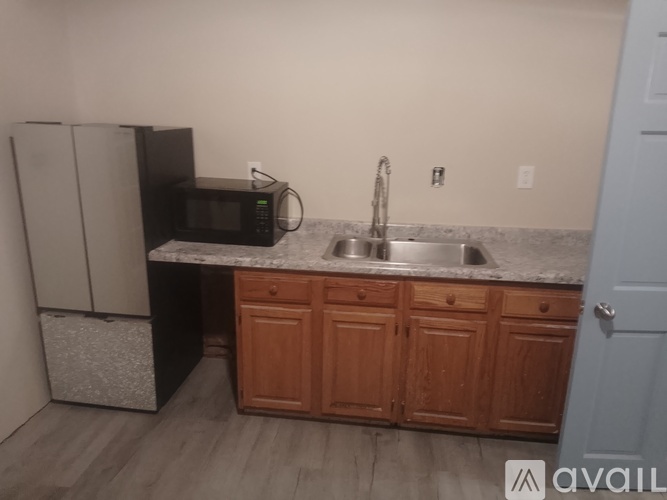 A kitchen with a black fridge, microwave, and a granite countertop.