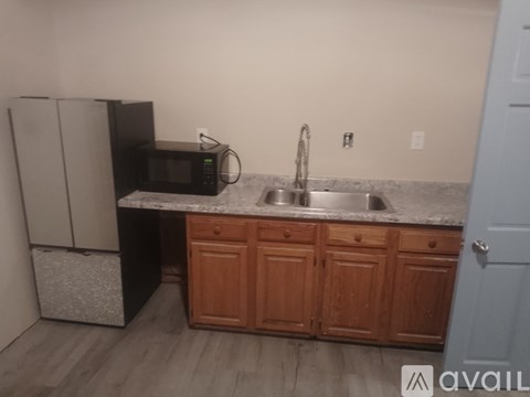 A kitchen with a black fridge, microwave, and a granite countertop.
