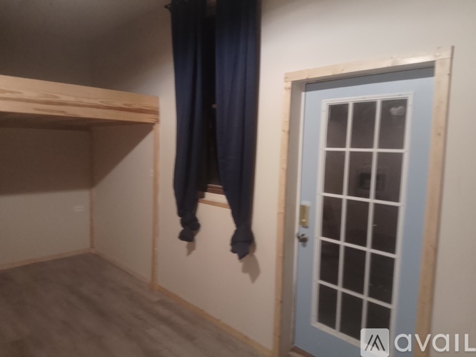 A room with a blue door and a window with a curtain.