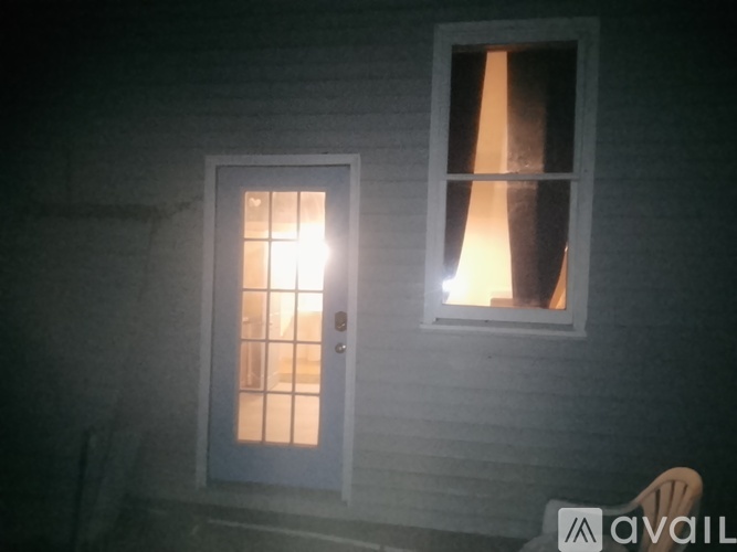 A house with a lit window and door at night.
