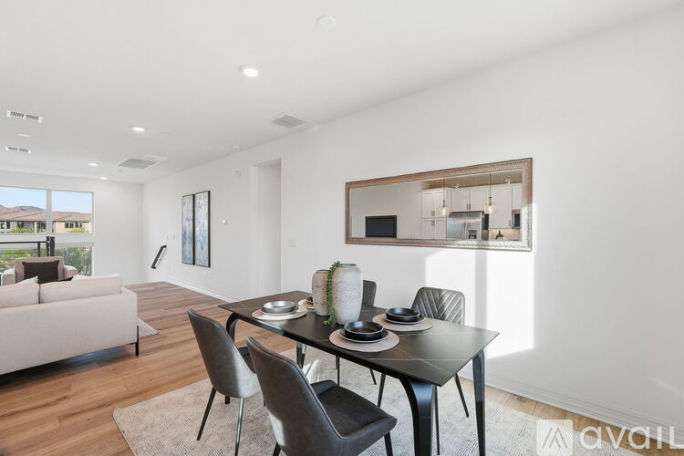 A modern dining room with a table set for two and a couch.