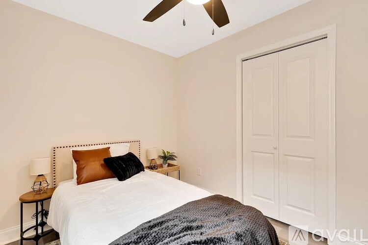 A bedroom with a bed, a ceiling fan, and a nightstand with a lamp.