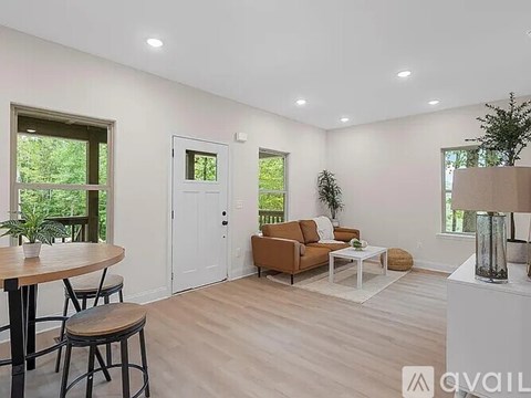 A living room with a brown couch, a white coffee table, and a wooden dining table with chairs.