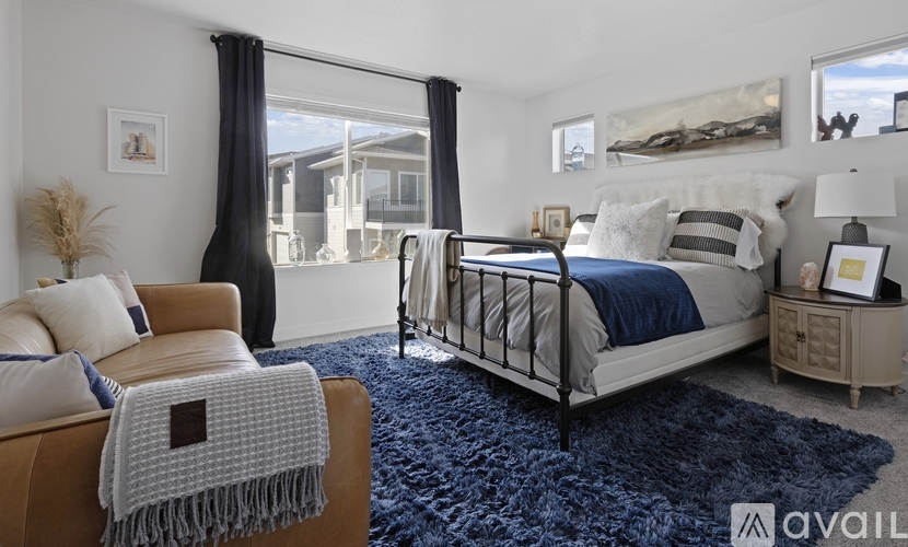 A bedroom with a bed, chair, and a rug.