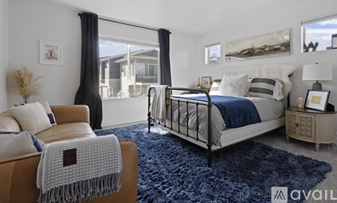 A bedroom with a bed, chair, and a rug.