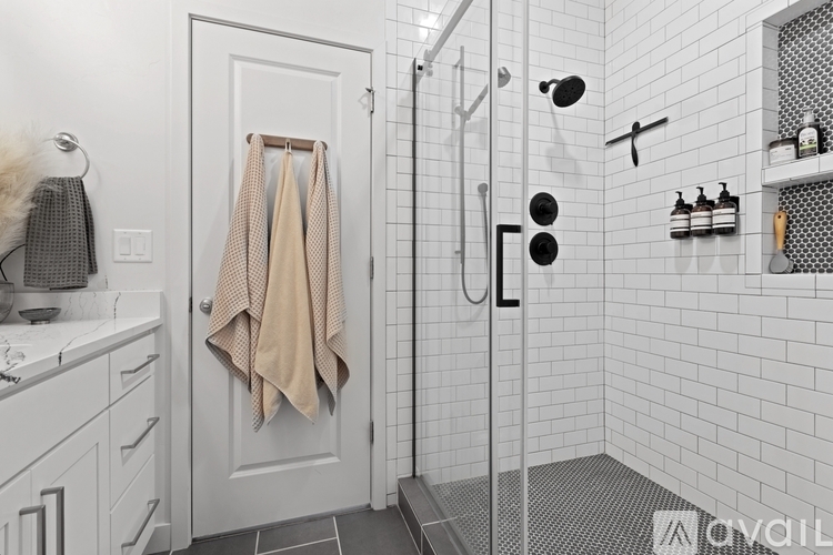 A bathroom with a white tiled shower and a white door.