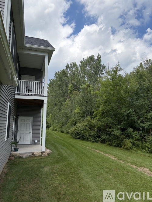 A house with a balcony overlooking a green lawn.
