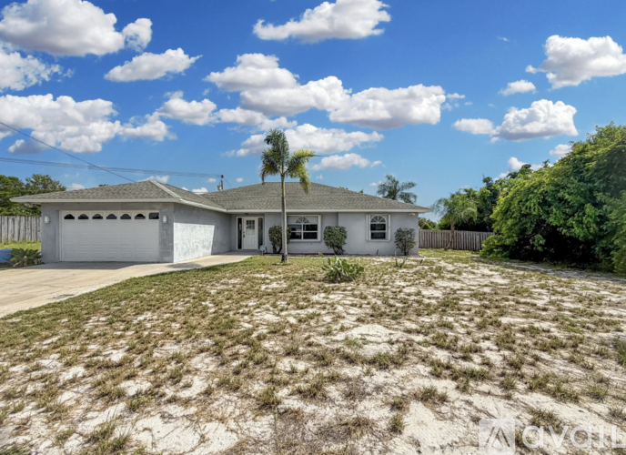 A house with a white exterior and a palm tree in front.
