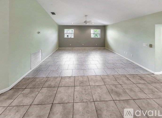 A spacious room with tile flooring and a ceiling fan.