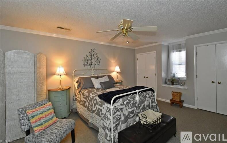 A bedroom with a bed, chair, and ceiling fan.