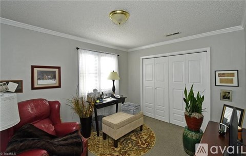 A living room with a red chair and a brown ottoman.
