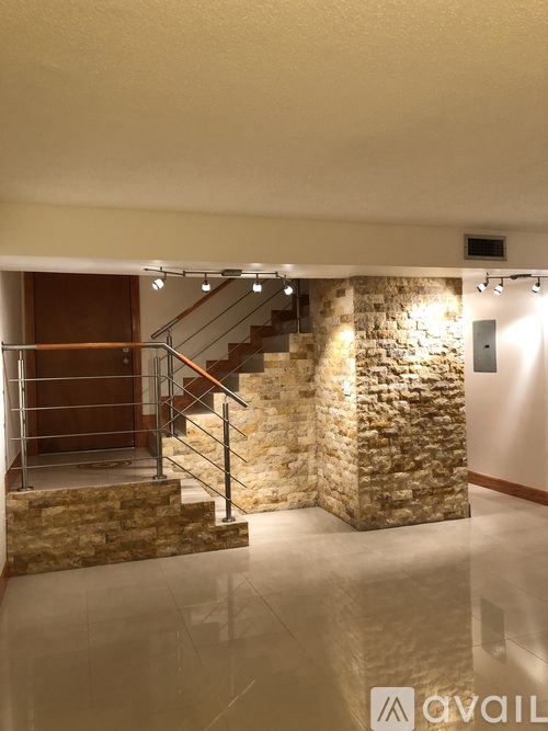 A stone staircase with a metal railing leads up to a door.