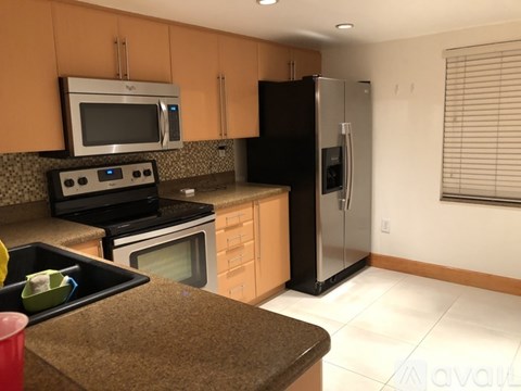 A kitchen with a black refrigerator and brown countertops.