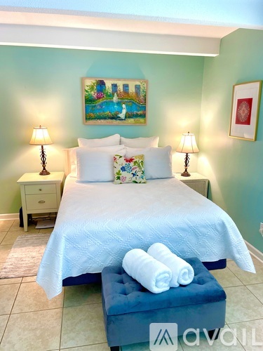 A bedroom with a bed, two lamps, a nightstand, and a painting on the wall.