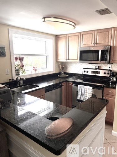 A kitchen with a black granite countertop and white cabinets.